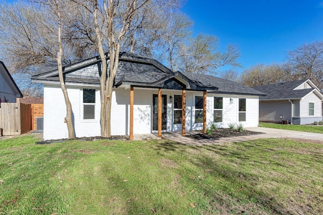 view of front of home featuring a front lawn, central air condition unit, and fence