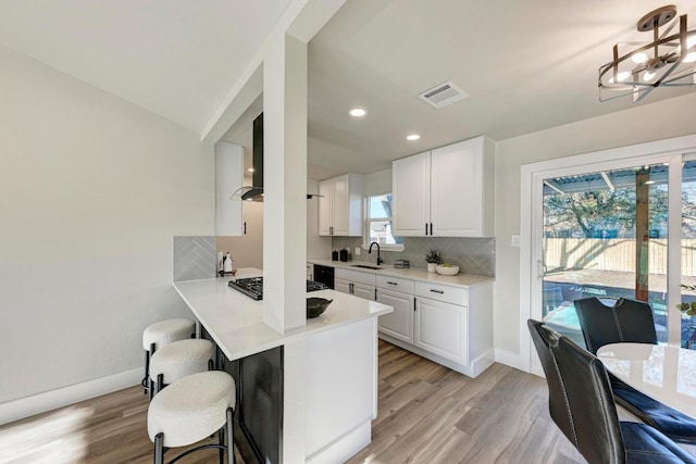 kitchen featuring visible vents, backsplash, a healthy amount of sunlight, a kitchen breakfast bar, and gas cooktop