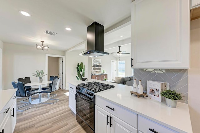 kitchen with visible vents, light wood-style flooring, island exhaust hood, black range with gas cooktop, and white cabinetry