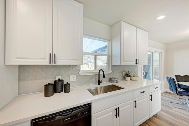 kitchen with light wood-type flooring, a sink, tasteful backsplash, white cabinets, and dishwasher