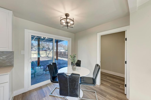 dining space with an inviting chandelier, light wood-style flooring, and baseboards