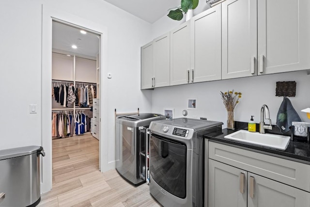 washroom with light wood finished floors, washer and clothes dryer, recessed lighting, cabinet space, and a sink