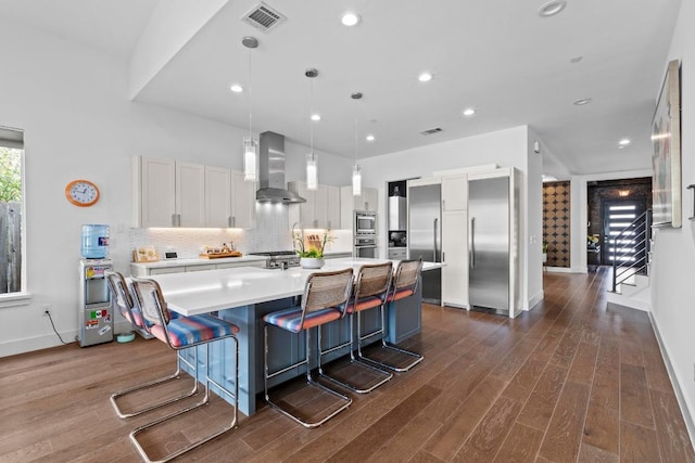 kitchen with visible vents, tasteful backsplash, wall chimney exhaust hood, white cabinets, and light countertops