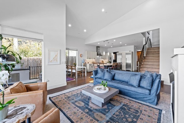 living area featuring high vaulted ceiling, wood finished floors, recessed lighting, baseboards, and stairs