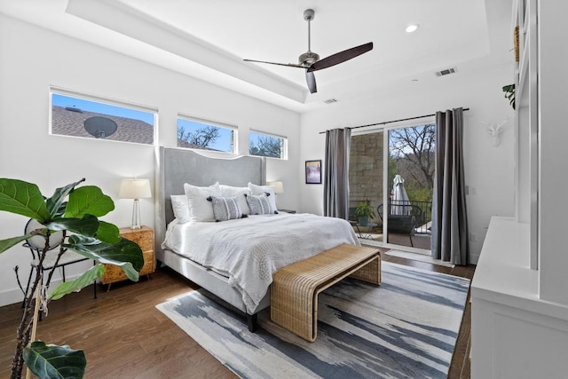 bedroom with wood finished floors, visible vents, a raised ceiling, and access to exterior