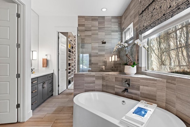 full bath featuring a soaking tub, tile walls, vanity, and a tile shower