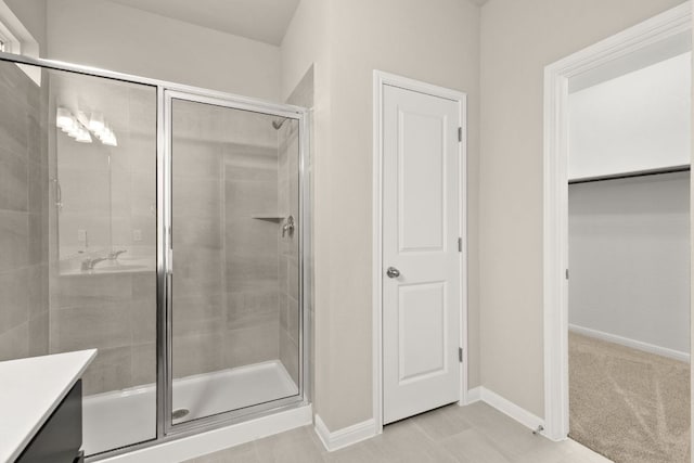 full bathroom with a stall shower, vanity, and baseboards