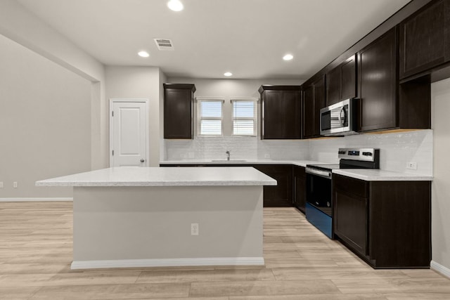 kitchen with visible vents, a kitchen island, a sink, decorative backsplash, and stainless steel appliances