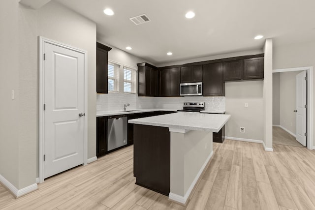 kitchen with a sink, stainless steel appliances, visible vents, and light wood-style flooring