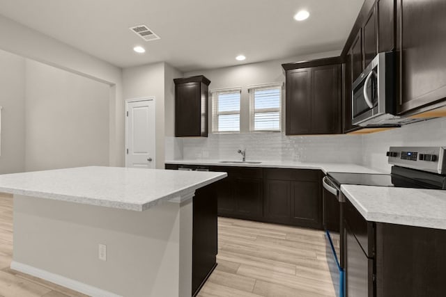 kitchen with tasteful backsplash, visible vents, a center island, appliances with stainless steel finishes, and a sink