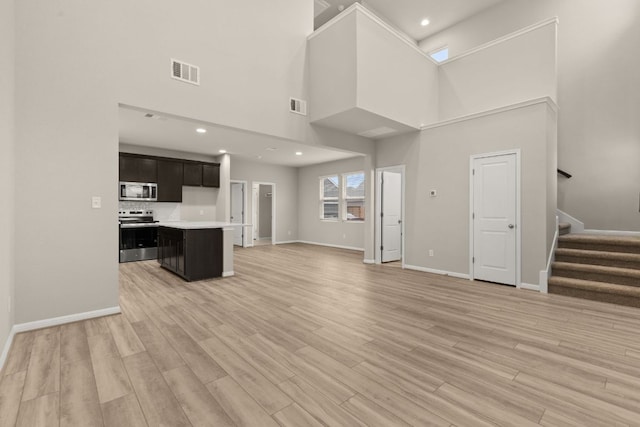 unfurnished living room featuring stairway, visible vents, and light wood finished floors