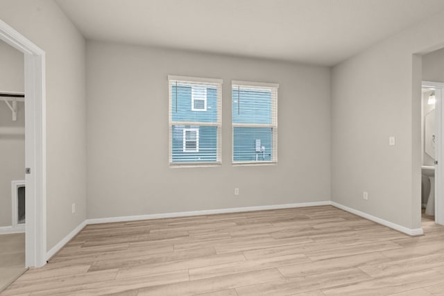 empty room featuring light wood-type flooring and baseboards