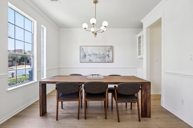 dining area with a chandelier, baseboards, ornamental molding, and light wood finished floors