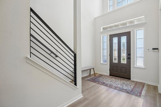 foyer featuring plenty of natural light, stairway, baseboards, and wood finished floors