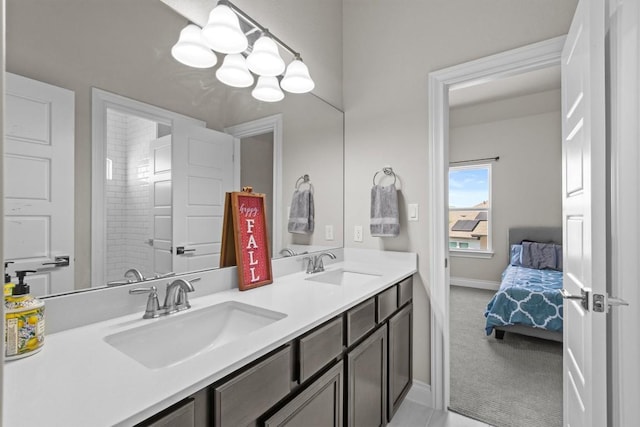 ensuite bathroom featuring double vanity, connected bathroom, baseboards, and a sink