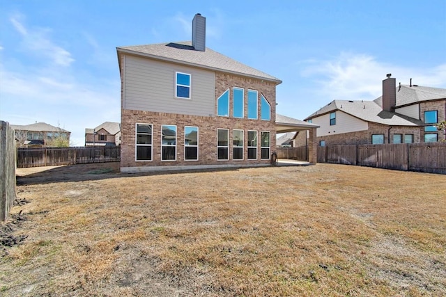 rear view of property with a yard, brick siding, and a fenced backyard