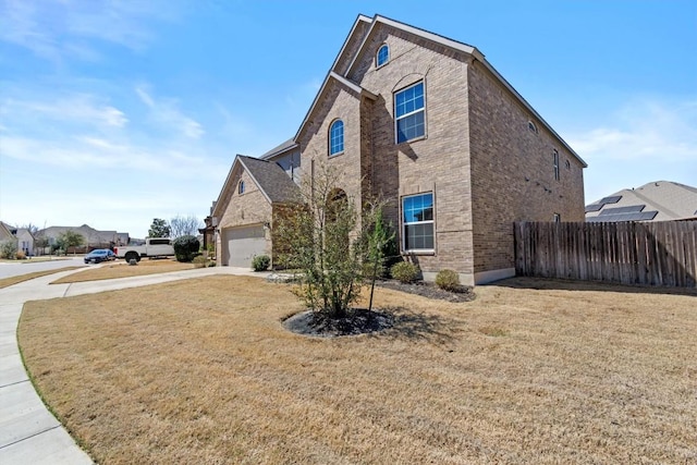 view of property exterior with brick siding, fence, a yard, a garage, and driveway