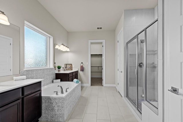 bathroom featuring visible vents, two vanities, a stall shower, a bath, and a spacious closet