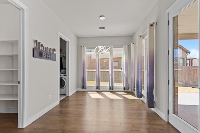 unfurnished dining area featuring visible vents, baseboards, an inviting chandelier, dark wood-style floors, and washer / clothes dryer