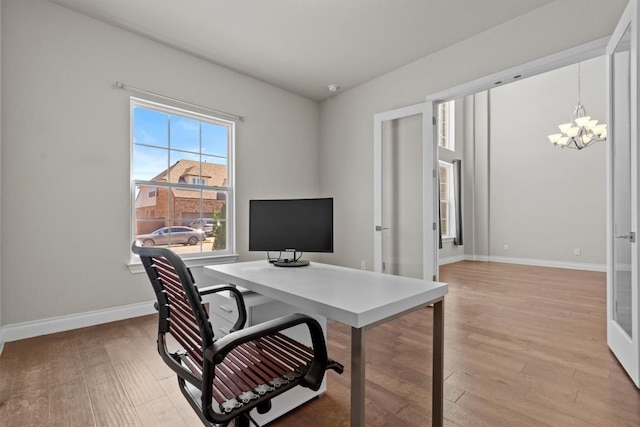 office space with light wood finished floors, a notable chandelier, and baseboards