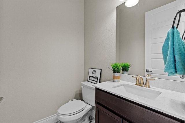 half bathroom featuring baseboards, toilet, and vanity