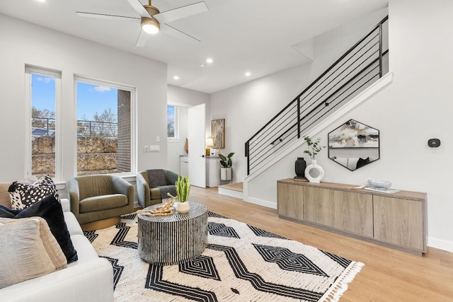 living room with recessed lighting, light wood-style floors, baseboards, ceiling fan, and stairs