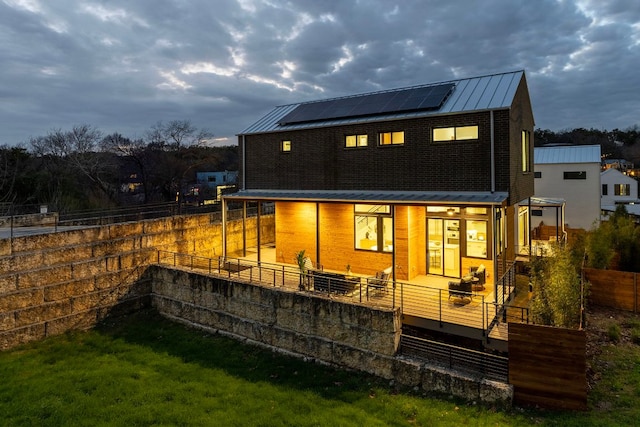 back of property with solar panels, metal roof, a standing seam roof, and fence