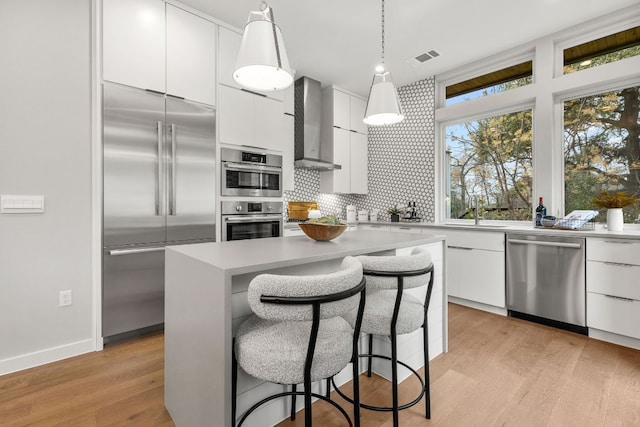 900 S 2nd St Unit 23, Austin, TX 78704 - kitchen with stainless steel appliances, wall chimney exhaust hood, modern cabinets, and white cabinetry