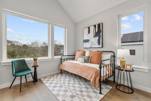 bedroom with lofted ceiling, wood finished floors, and baseboards