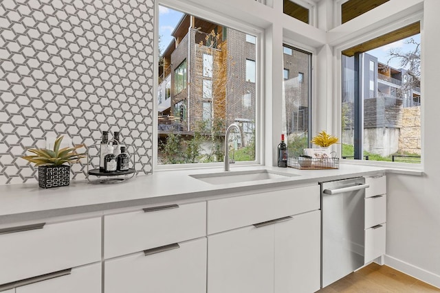 900 S 2nd St Unit 23, Austin, TX 78704 - kitchen featuring stainless steel dishwasher, a sink, light countertops, and white cabinets