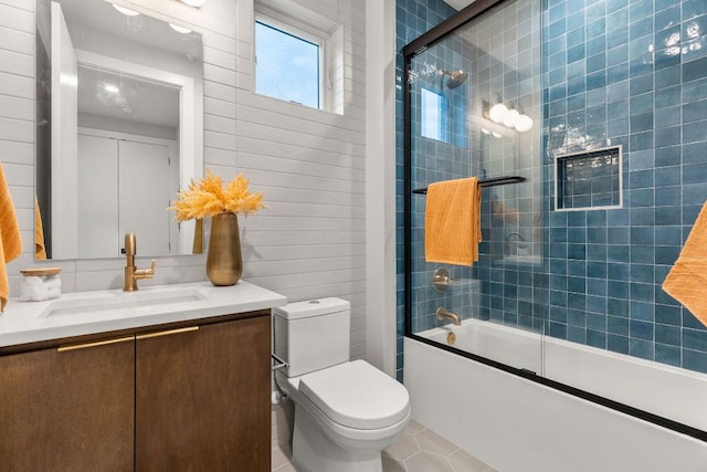 bathroom featuring tile patterned floors, toilet, vanity, and bath / shower combo with glass door