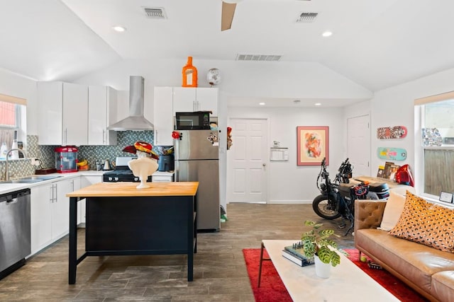 kitchen with visible vents, lofted ceiling, a sink, black appliances, and wall chimney exhaust hood