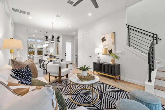 living room with stairs, visible vents, and light wood finished floors