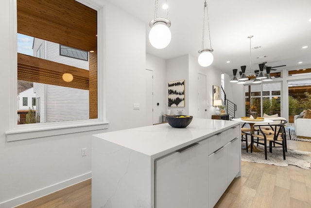 kitchen featuring light wood finished floors, hanging light fixtures, white cabinetry, modern cabinets, and a center island