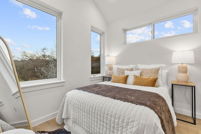 bedroom with baseboards, wood finished floors, and vaulted ceiling