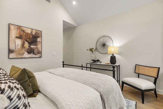 bedroom featuring attic access, wood finished floors, baseboards, and lofted ceiling