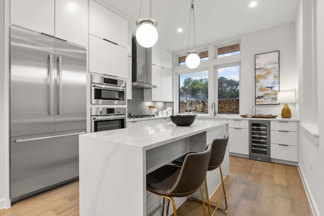 kitchen featuring backsplash, beverage cooler, stainless steel appliances, white cabinetry, and modern cabinets