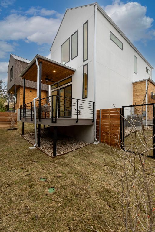 back of property with a yard and a ceiling fan