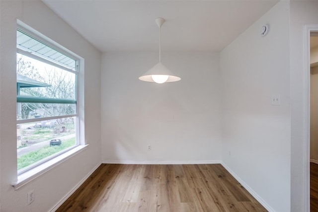 unfurnished dining area with baseboards and wood finished floors