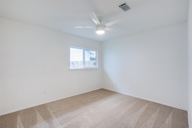 carpeted spare room with baseboards, visible vents, and ceiling fan