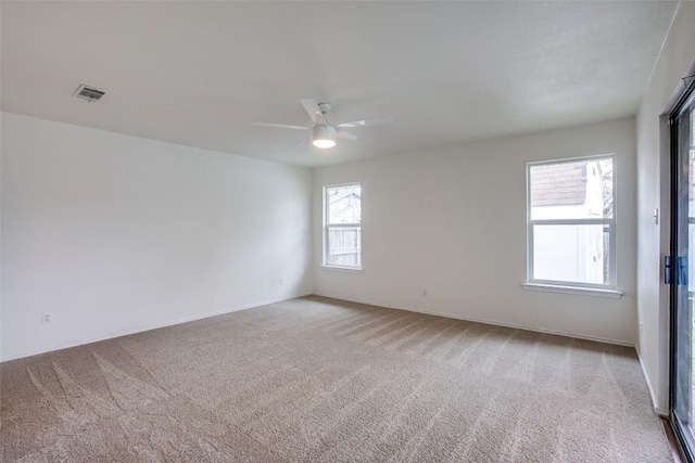 empty room with baseboards, light colored carpet, visible vents, and ceiling fan