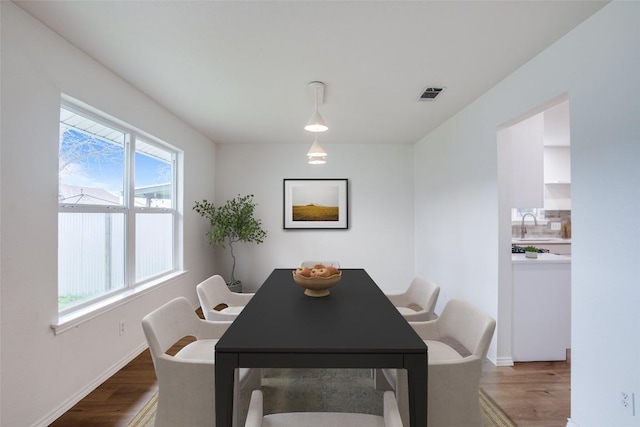 dining room featuring visible vents, baseboards, and wood finished floors