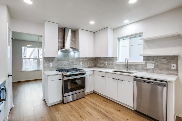 kitchen with a sink, light countertops, wall chimney range hood, and stainless steel appliances