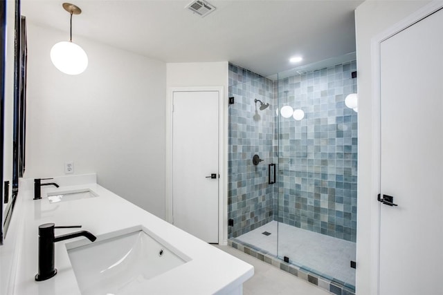 bathroom with a shower stall, double vanity, visible vents, and a sink