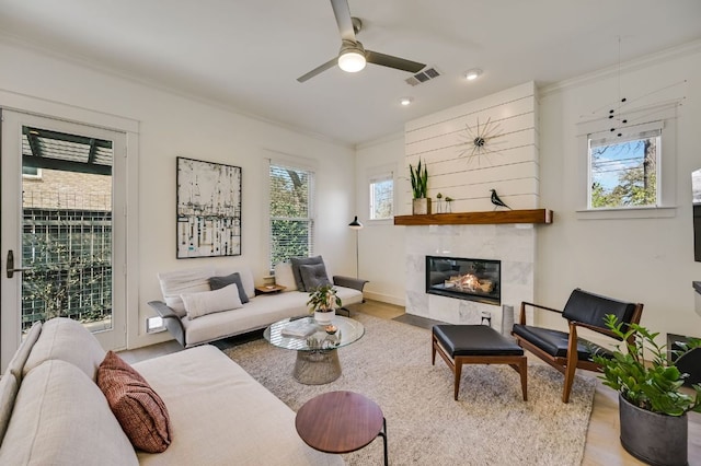 living area with a wealth of natural light, visible vents, and ornamental molding