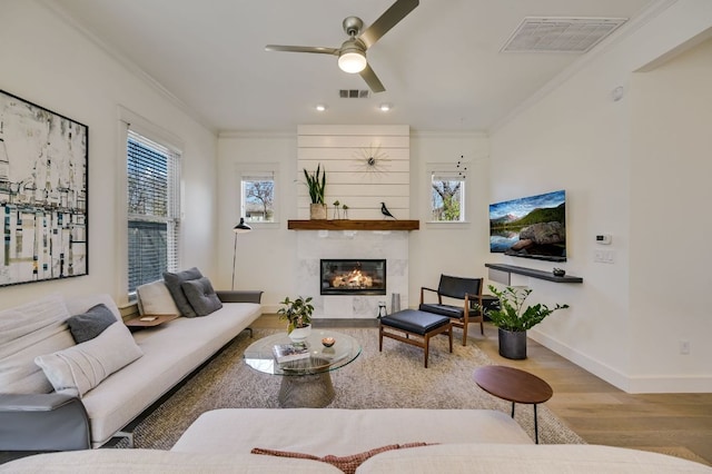 living room featuring wood finished floors, visible vents, and ornamental molding