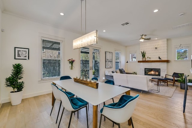 dining space with a wealth of natural light, visible vents, light wood-style floors, and a fireplace