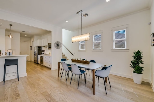 dining area featuring baseboards, crown molding, and light wood-style floors