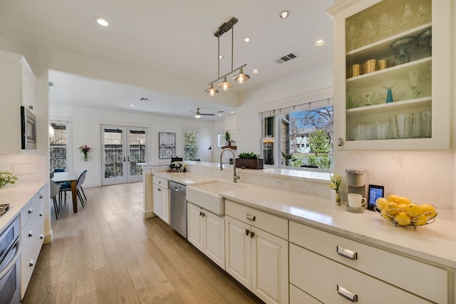 kitchen with light wood finished floors, visible vents, appliances with stainless steel finishes, french doors, and a sink