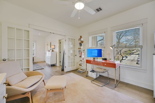 home office with a ceiling fan, wood finished floors, visible vents, baseboards, and french doors